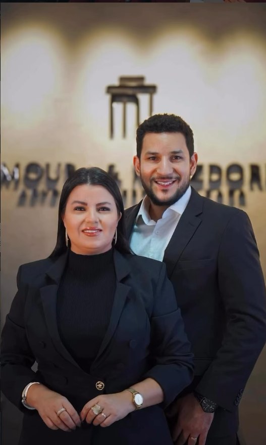 Dra. Tatiana Metzdorf Viana e Dr. Leandro Rodrigues de Moura, sócios do escritório, diante da logo Moura & Metzdorf
